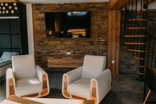 a living room with two chairs and a tv at Luxusní Apartmány Domovjanka - LYSÁ HORA, SMRK, KMÍNEK, SLAVÍČ in Bílá