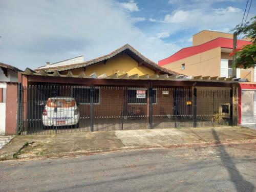 un edificio con una valla con un coche aparcado en él en Casa de temporada Praia Grande, en Praia Grande