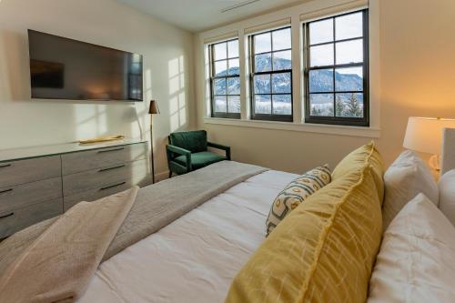 a bedroom with a bed with a television and a chair at Academy Place | Glacier Lily Penthouse in Crested Butte