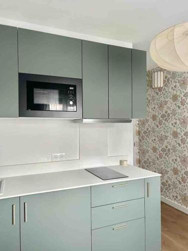 une cuisine avec des armoires blanches et un micro-ondes dans l'établissement M33 superbe studio centre ville, à Annemasse