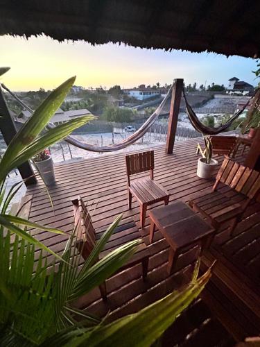 a wooden deck with two chairs and a hammock at Sunset Valley Bungalow in Camocim