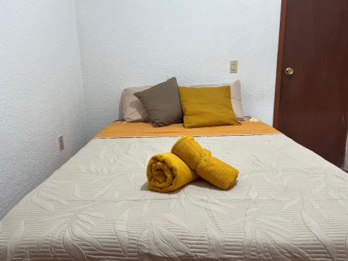 a bed with two yellow towels on top of it at Departamento Río Verde in San Cristóbal de Las Casas