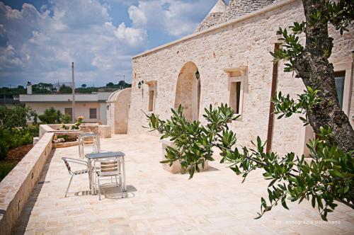 a patio with chairs and a table and a building at Trulli Magravì - Apparthotel in Alberobello