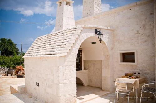 a white stone building with a table and a table and chairs at Trulli Magravì - Apparthotel in Alberobello