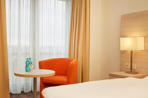 a hotel room with a bed and a chair and a table at H+ Hotel Limes Thermen Aalen in Aalen
