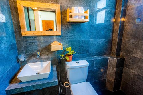 a bathroom with a sink and a toilet and a mirror at Minthara Holiday Home & Restaurant in Talawatugoda