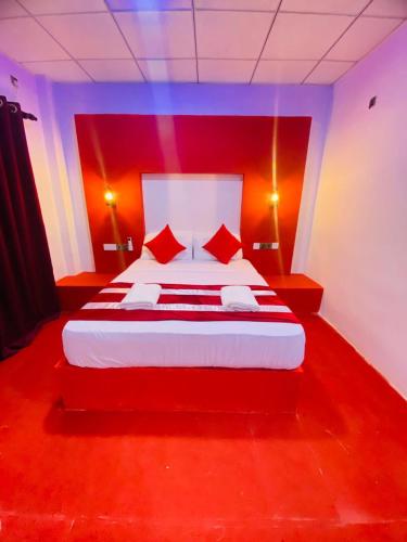 a red bedroom with a white bed with red pillows at Wilroma Hotel&Resort in Anuradhapura