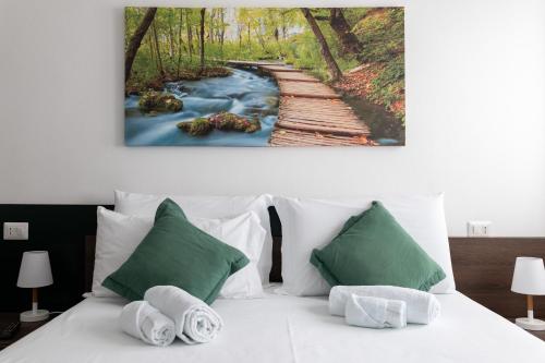 a bed with green and white pillows and a river at B&B I LAKE IT BELLAGIO in Bellagio