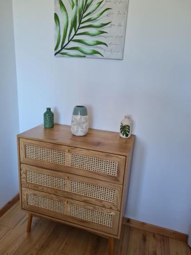 a wooden dresser against a white wall with a painting at GITE EN CAMPAGNE 15 min de Rennes in Saint-Gilles