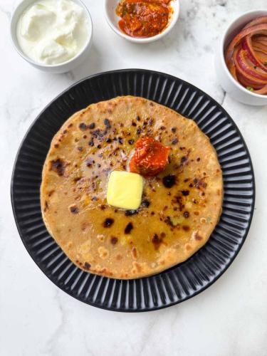 a tortilla with a pat of butter on a plate at Hotel The Katra Avenue in Katra