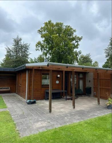 a large wooden house with a patio at Bungalow de Zwaluw in Biddinghuizen