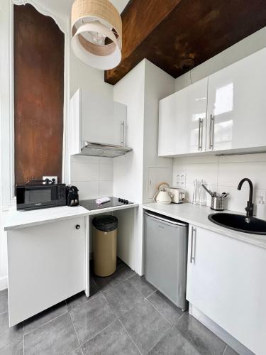une cuisine blanche avec des armoires blanches et un évier dans l'établissement Les lices, centre ville de Rennes, à Rennes
