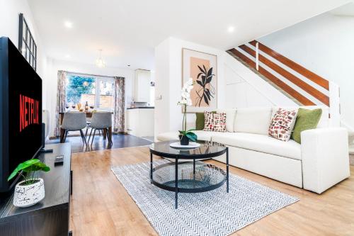 ein Wohnzimmer mit einer weißen Couch und einem Tisch in der Unterkunft 3 BDR House near East Croydon Rail Station in Croydon