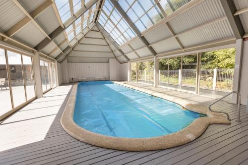 an indoor swimming pool with a glass roof at Avon - Waterfront Retreat in Goon Nure