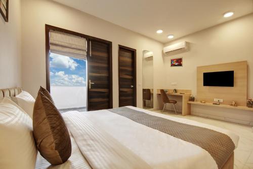 a bedroom with a large bed and a television at Limewood Stay - Corporate Huda City Centre in Gurgaon