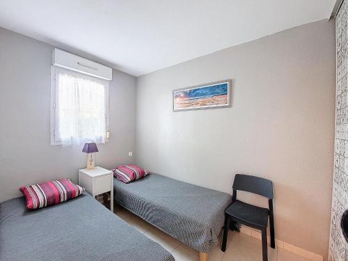 - une chambre avec 2 lits jumeaux et une chaise dans l'établissement S-Plage 02-Soustons Joli petit appartement avec jardin et piscine pour 4 personnes, à Vieux-Boucau-les-Bains