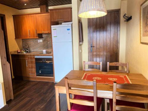 une cuisine avec une table en bois et un réfrigérateur blanc dans l'établissement Acogedor apartamento en Font Romeu-Via I, à Font-Romeu
