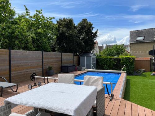 eine Terrasse mit Tisch und Stühlen neben einem Swimmingpool in der Unterkunft La Maison des Rêves - 8 pers - Centre - Rêve au Mans in Le Mans