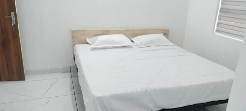 a white bed with white sheets and pillows at Little home apartment in Kozhikode