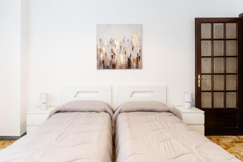 a bedroom with two beds and a painting on the wall at Case da Amare - Casa Tobia in Alassio