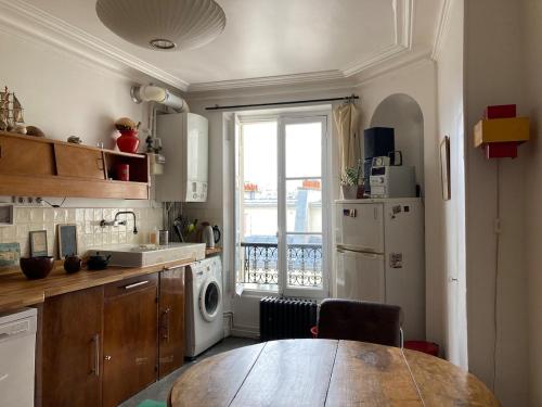 une cuisine avec une table en bois et une fenêtre dans l'établissement Luminous and inspiring arty home, à Paris