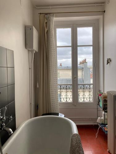 une baignoire dans une salle de bain avec une fenêtre dans l'établissement Luminous and inspiring arty home, à Paris