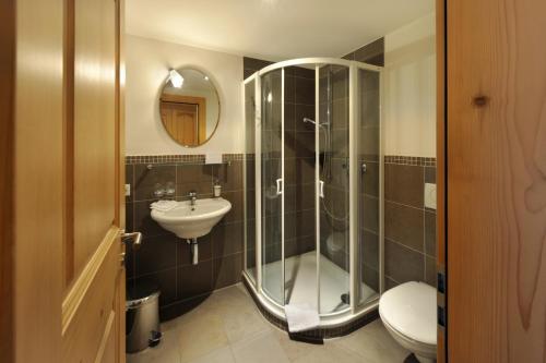 ein Bad mit einer Dusche, einem Waschbecken und einem WC in der Unterkunft Hotel Bellerive Gstaad in Gstaad