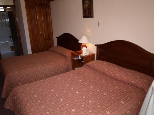 a hotel room with two beds and a lamp on a table at Qelqatani Hotel in Puno