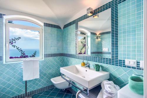 a blue tiled bathroom with a sink and a window at POSEA Collection - Villa Ponente in Positano