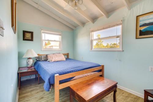 a bedroom with a bed and a table and two windows at 5 Mi to Beach Bay St Louis Home with Launch and Dock in Shoreline Park