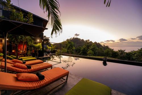 a pool with several lounge chairs next to the water at Sumba Lodge in Manuel Antonio