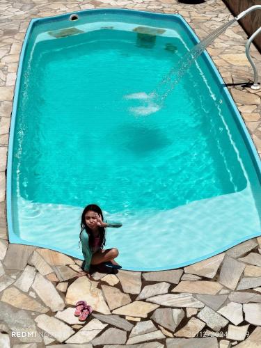 a little girl sitting next to a swimming pool at Pousada Canto Juquehy in Juquei