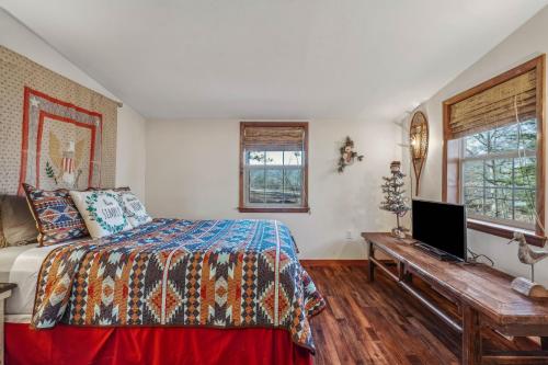 a bedroom with a bed and a desk with a television at Cottage Inn The Woods -- Pond, Pet Friendly, Grill, Wifi, Fire Pit, Deck, Screen Porch, Fireplace, Private in Berkeley Springs