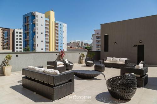 a patio with couches and chairs on a rooftop at Belo Estúdio Elegante em Poço de Caldas PGO0205 in Poços de Caldas
