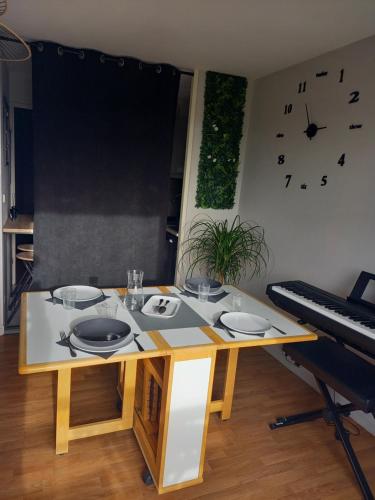 une table avec des assiettes et un piano dans une pièce dans l'établissement Appart Mémorial 2-4pers, à Caen