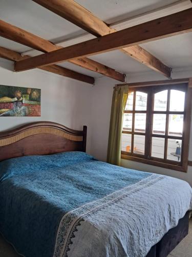 a bedroom with a blue bed and a window at Hostal Valentino in Villarrica