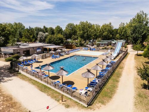 eine Draufsicht auf einen Pool mit Stühlen und Sonnenschirmen in der Unterkunft Domaine Résidentiel de Plein Air Les Demoiselles in Saint-Hilaire-de-Riez