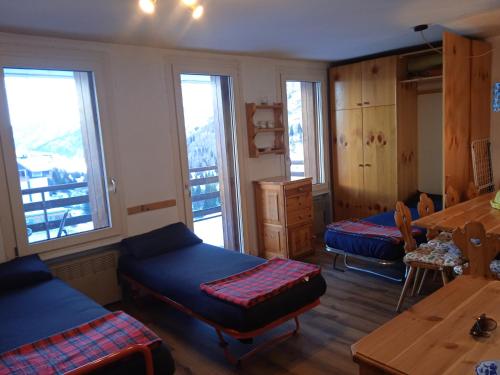 a room with two beds and a table and windows at Mountain Shelter in Passo del Tonale