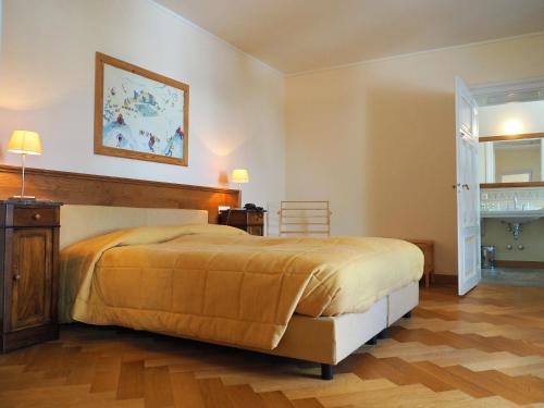 a bedroom with a large bed and a wooden floor at Maloja Palace Suites CO2-Neutral in Maloja