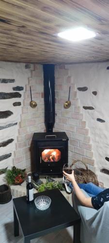 a woman sitting on a couch in front of a fireplace at Casa rural La calleja de las hurdes TRCC00555 in Sauceda
