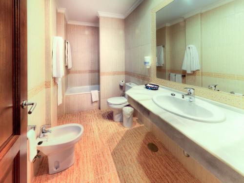 a bathroom with a sink and a toilet and a mirror at Hotel Porfirio in Zahara de los Atunes