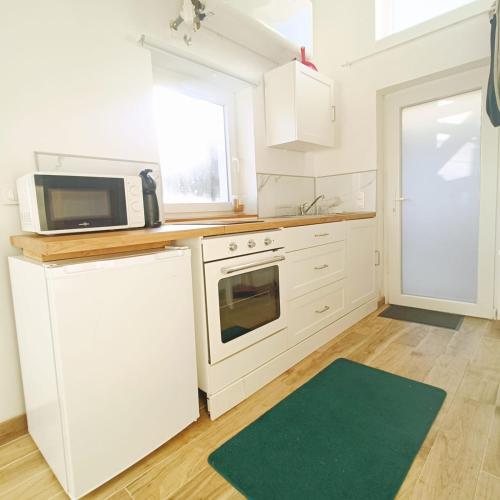 - une cuisine avec des placards blancs, un four micro-ondes et un tapis vert dans l'établissement Nest- Tiny house avec Jardin, proche gare, Luxembourg-Metz, à Uckange
