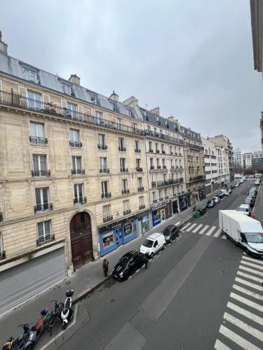 une rue urbaine vide avec un grand bâtiment et des voitures dans l'établissement Cozy studio Bastille, à Paris