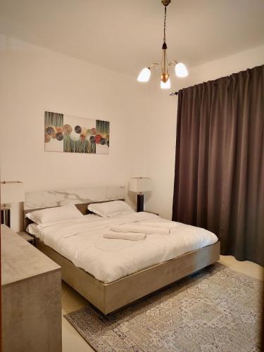 a bedroom with a large bed with white sheets at Cozy 1Bhk With Corniche View in Sharjah