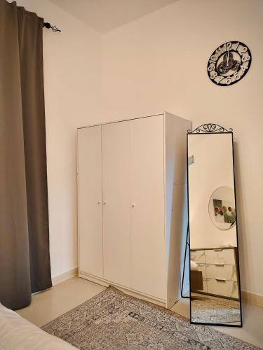 a mirror next to a white cabinet in a bedroom at Cozy 1Bhk With Corniche View in Sharjah