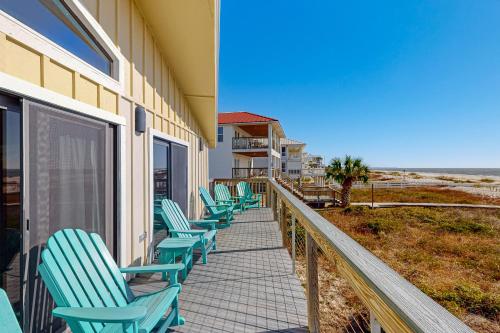 a row of chairs on a walkway next to a beach at As Pelicans Pass in Indian Pass