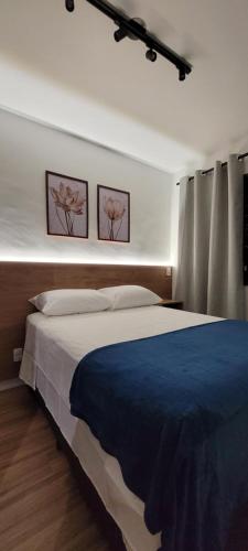 a bedroom with a large bed with two pictures on the wall at STUDIO104 - Novo e completo na melhor localização de Pinheiros, próximo ao Metrô Fradique Coutinho in Sao Paulo