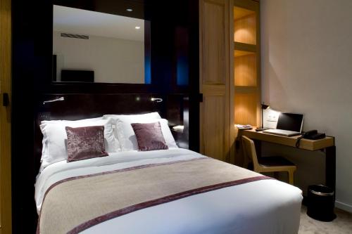 une chambre avec un lit et un bureau avec un ordinateur portable dans l'établissement Marceau Champs-Elysées, à Paris