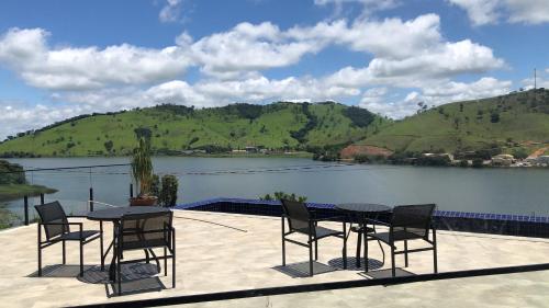 a patio with tables and chairs next to a lake at Pousada Varandas do Lago in Capitólio