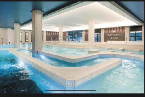 une grande piscine avec de l'eau bleue dans un immeuble dans l'établissement appartement 5min gare RER Disneyland Paris val d'Europe la vallée Village parking inclus, à Montévrain